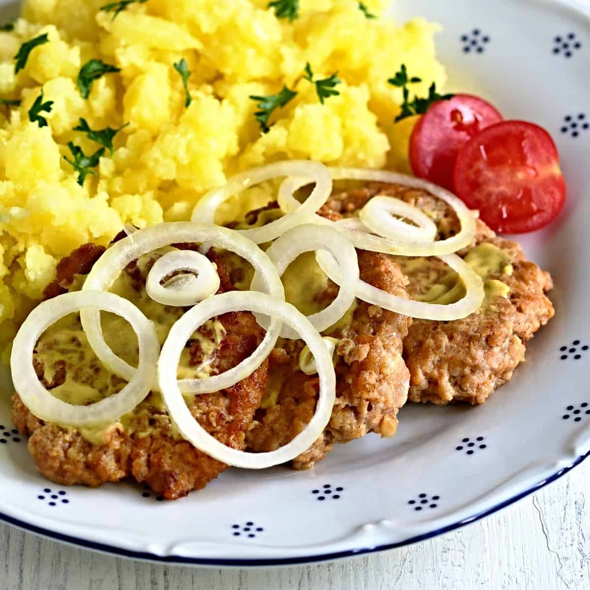 pork patties served with onion circles and potatoes