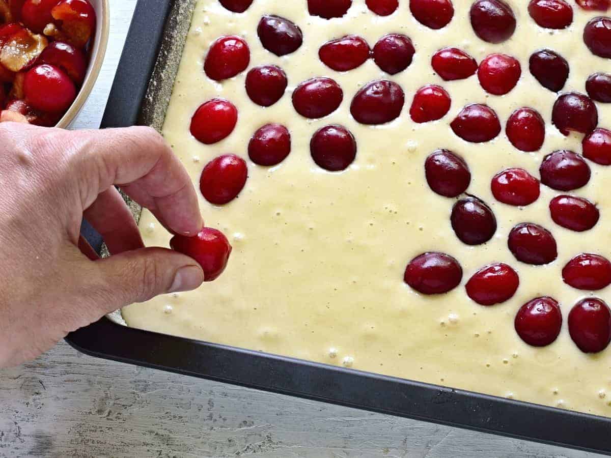 topping a cake batter with cherries