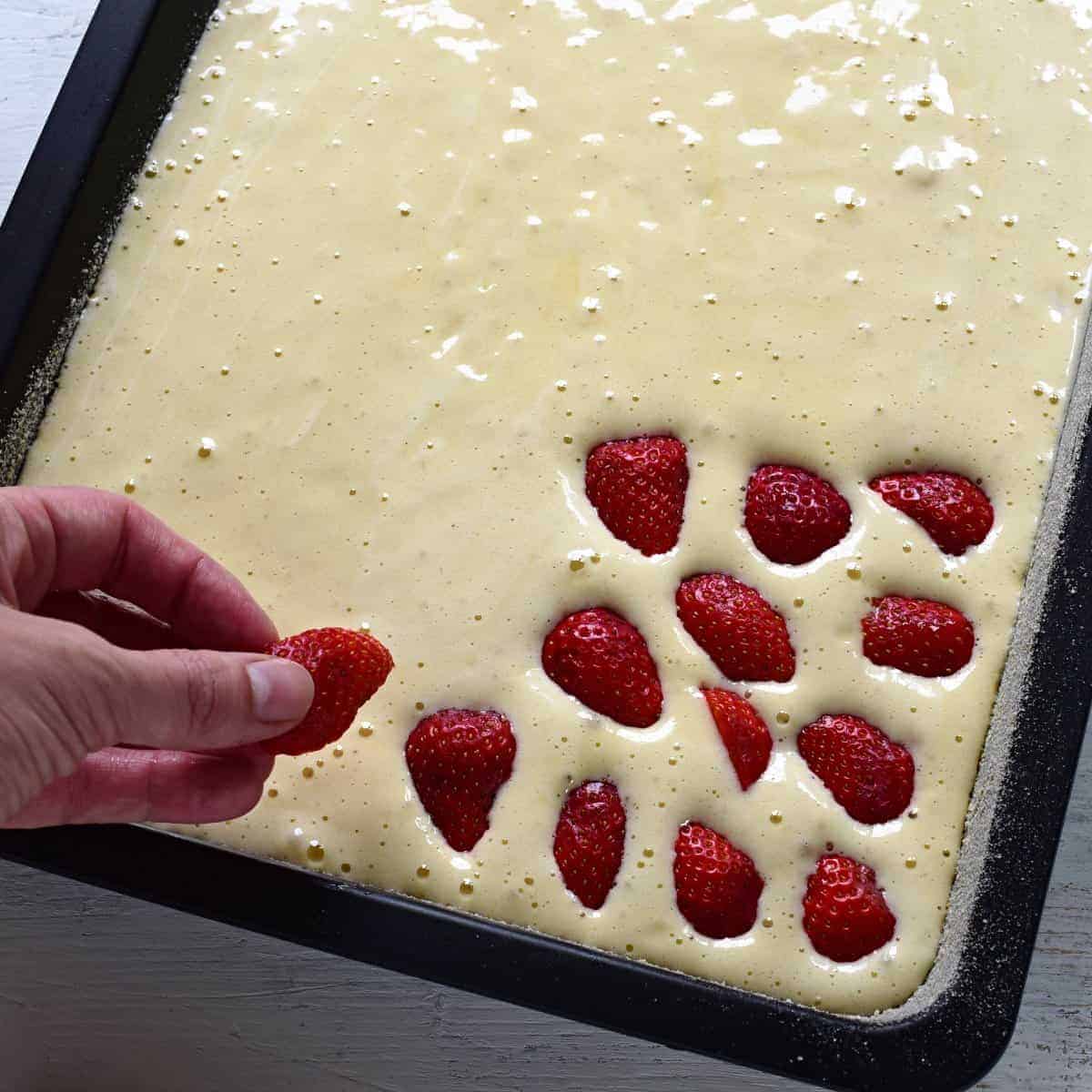 putting strawberries on a batter