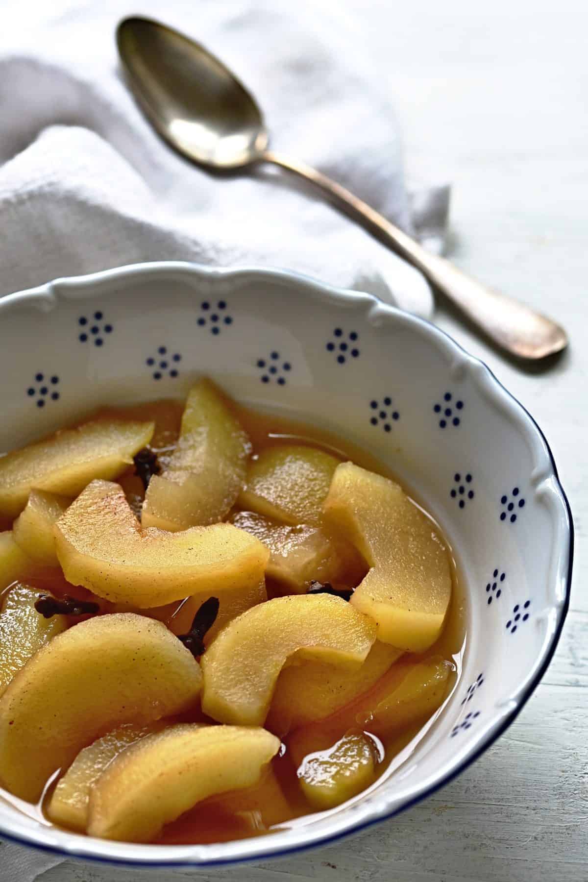Spiced apple compote served warm in a bowl with a spoon.