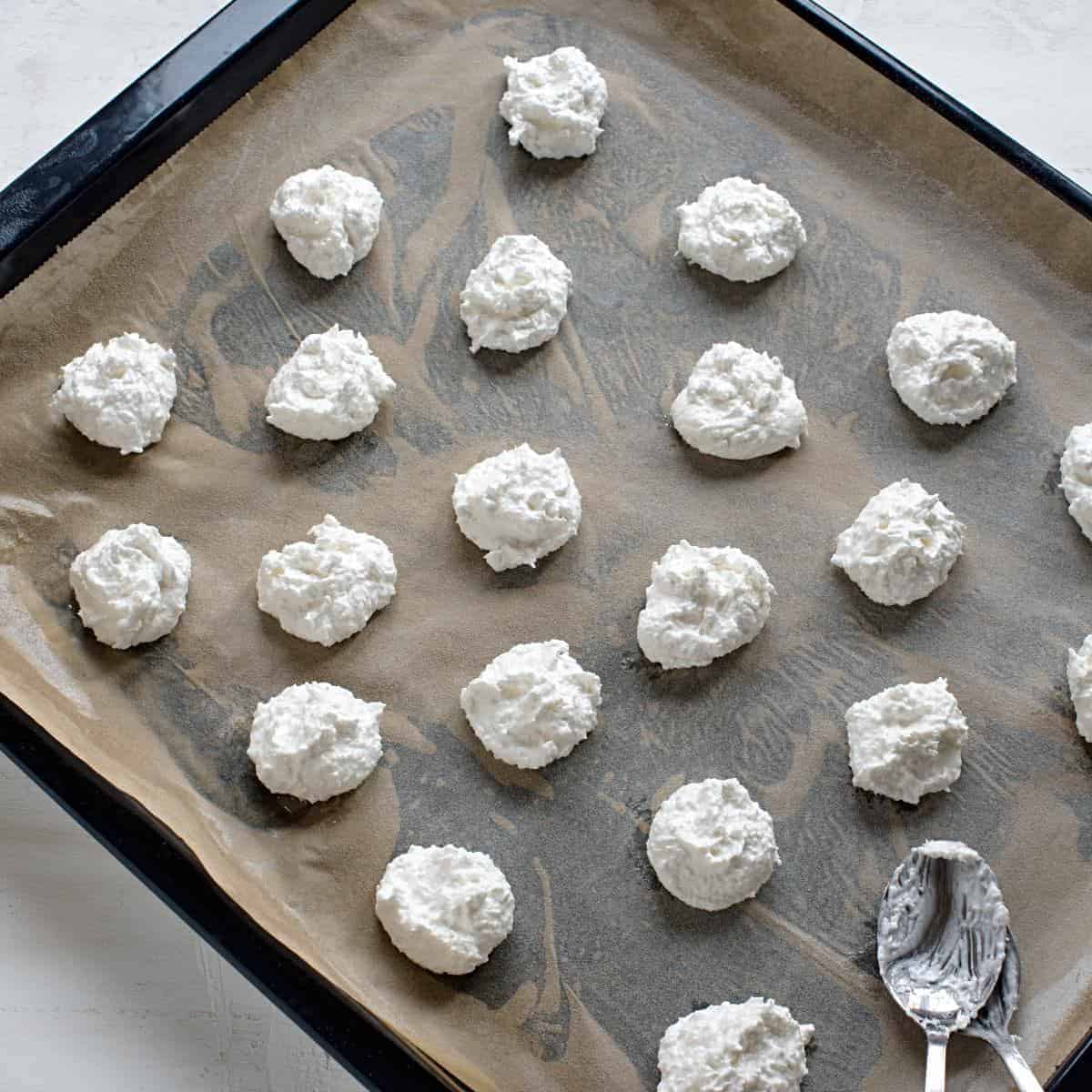 Shaping coconut meringue cookies on a baking sheet.