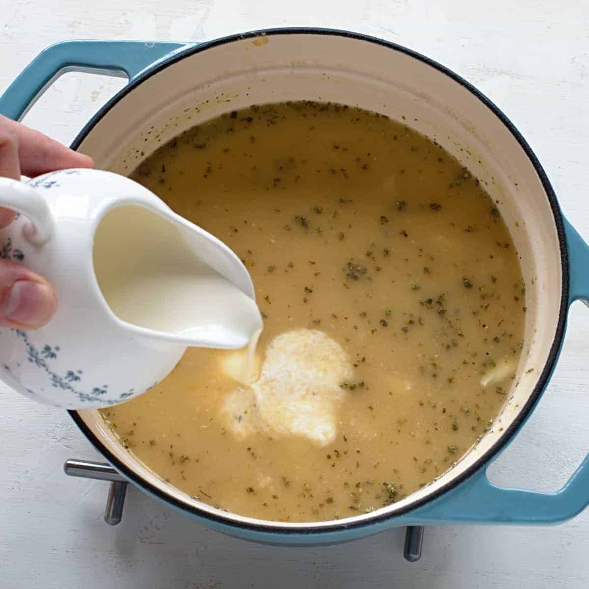 Pouring heavy cream in split pea soup.