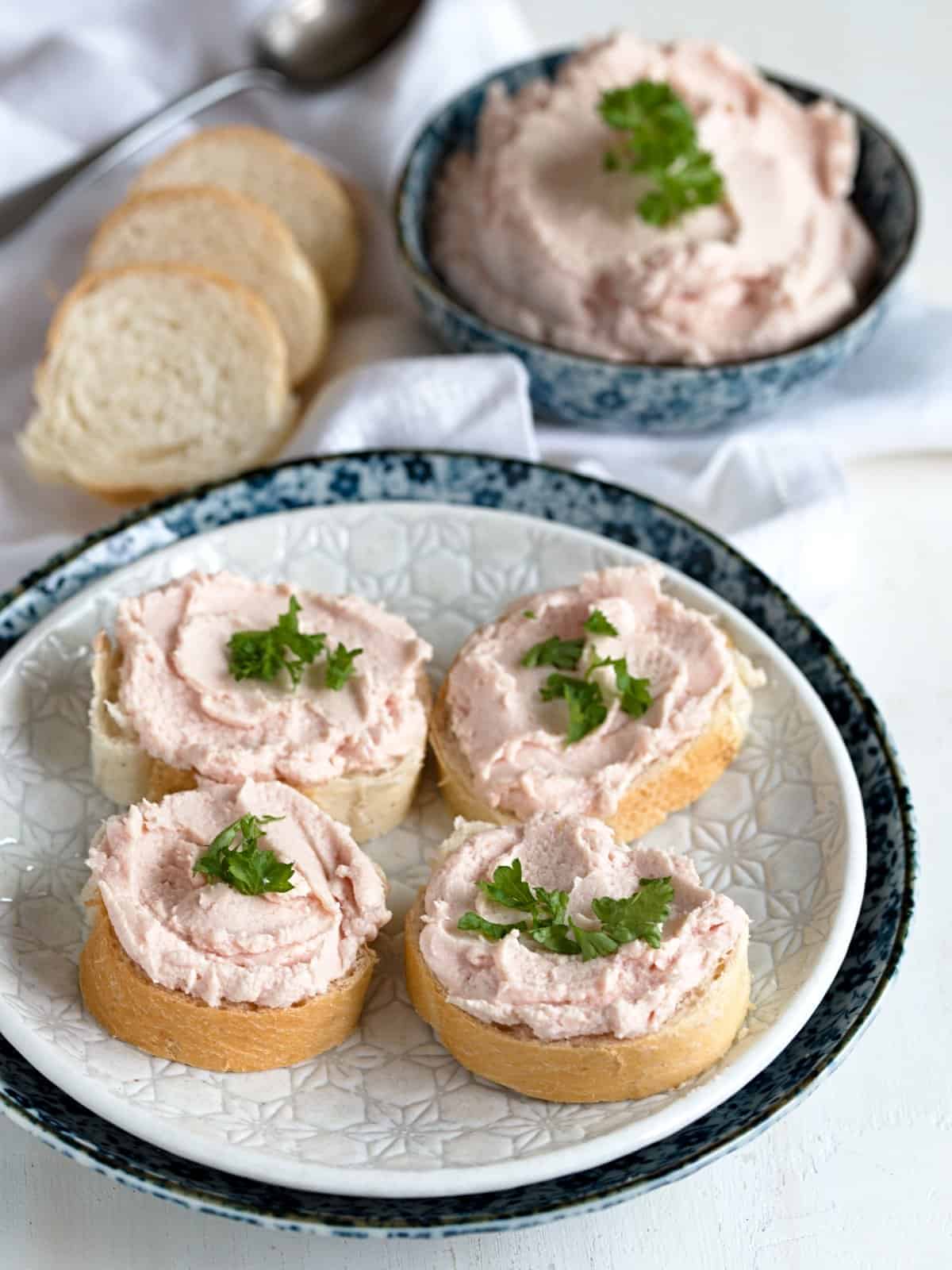 Ham spread on white bread slices, garnished with green parsley. 