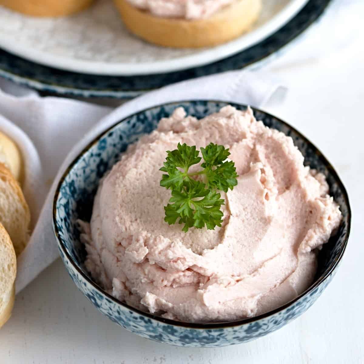 Ham spread in a bowl, garnished with green parsley. 